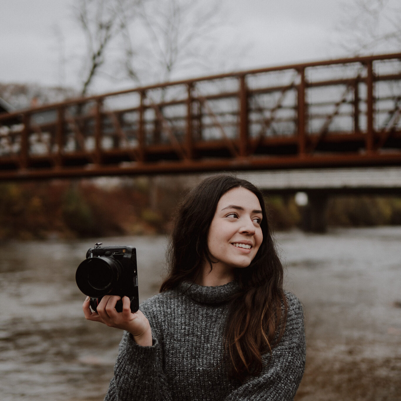 Golubski Photography standing confidently in front of the iconic Cuyahoga Valley National Park bridge, holding a camera and ready to capture the beauty of the moment